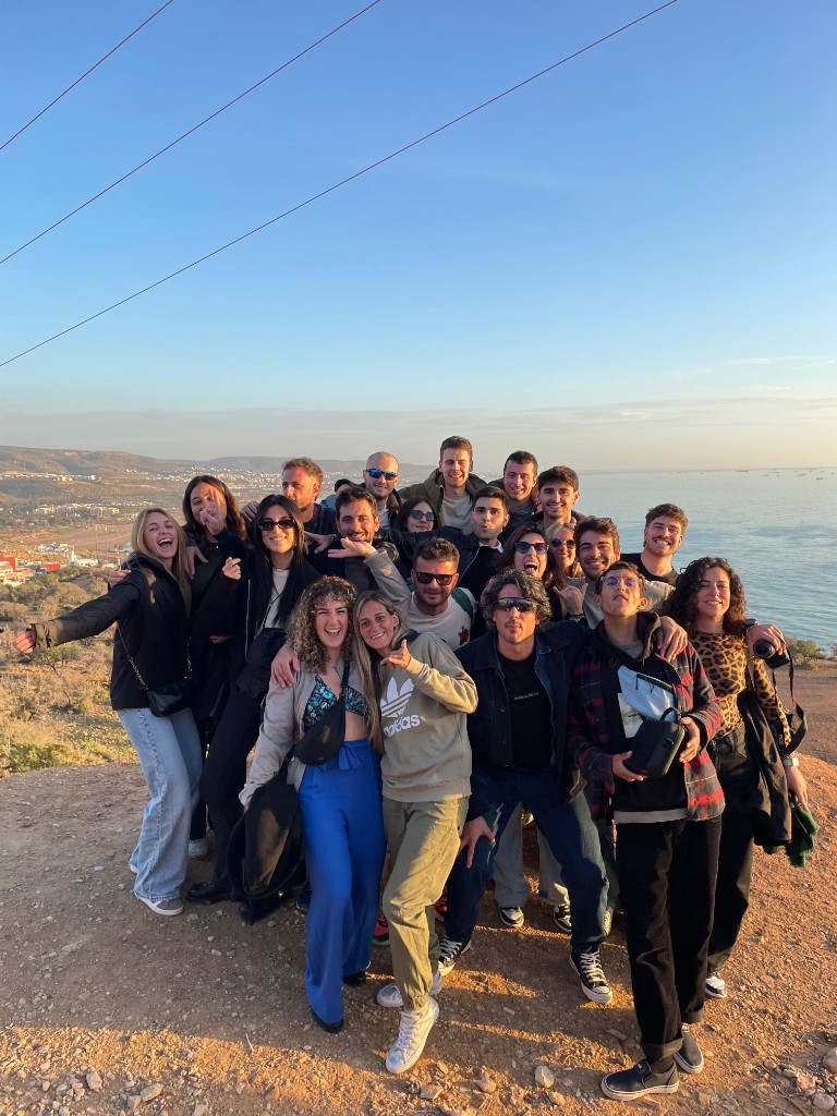Friends gathered on a hilltop overlooking Tamraght, the Atlantic, and the mountains